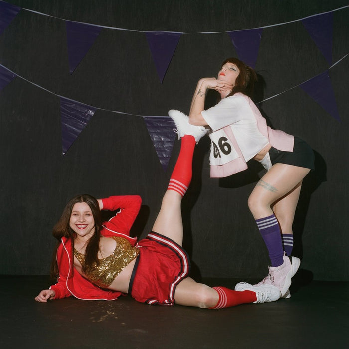 models in alt cheer leading outfits posing in front of a black set one laying down with their leg up one posing of the foot of the other.