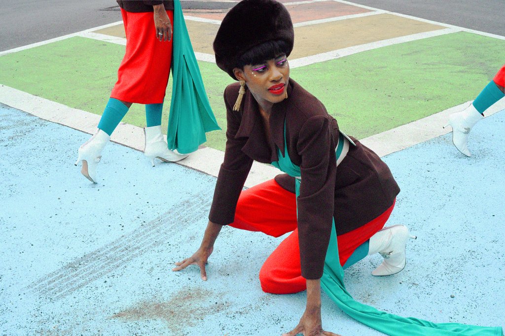 model crouching on painted pavement and white boots walking on either side of here.