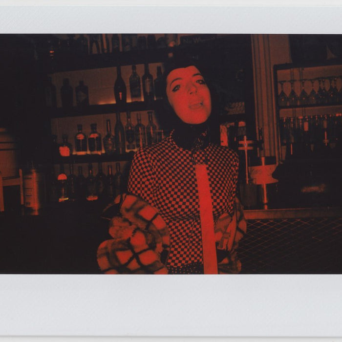 person posing, bar in the background, all red effect in polaroid style. 