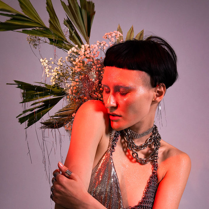portrait of a model in a silver look surrounded by a floral set. 