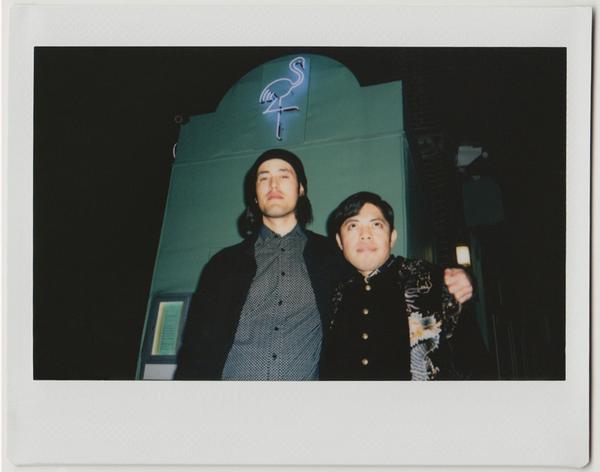 employees posing, neon flamingo bar entrance behind - polaroid style.