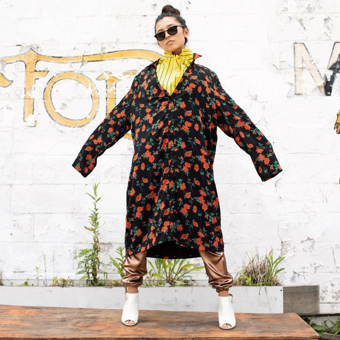 alana murau in striped top and floral print coat standing in front of painted wall.