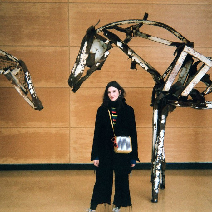 person posing between horses sculptures.