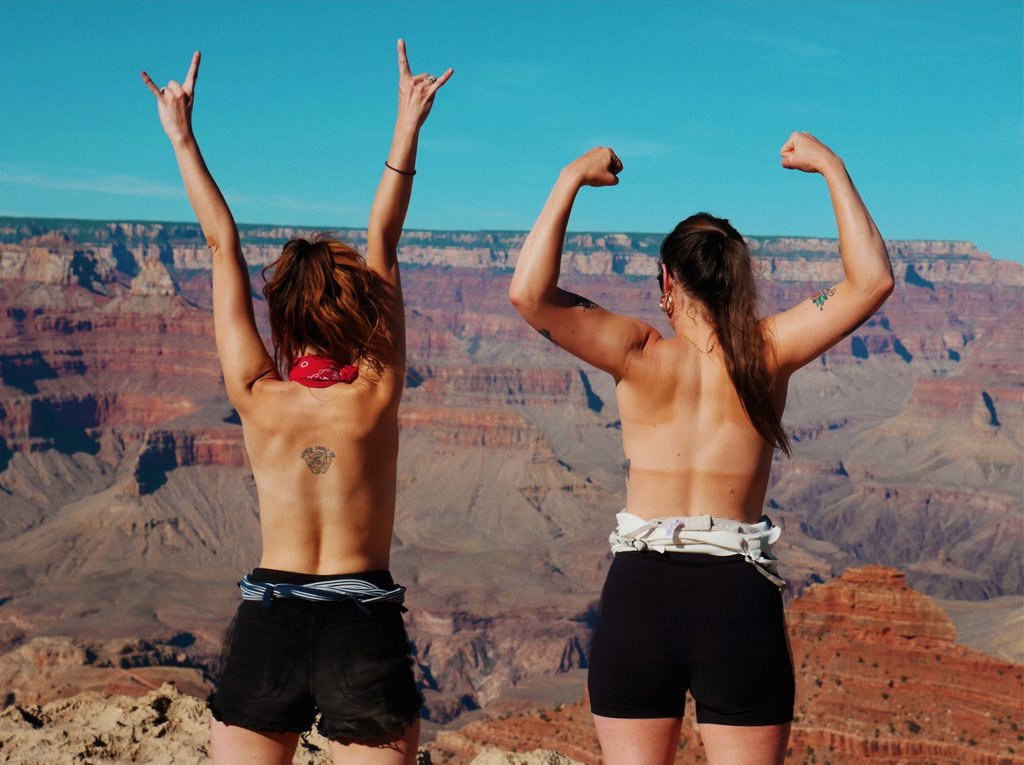 duo with their arms raised in the air at the grand canyon.