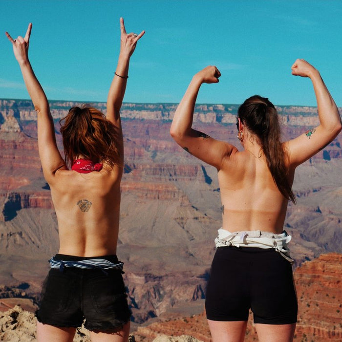 duo with their arms raised in the air at the grand canyon.