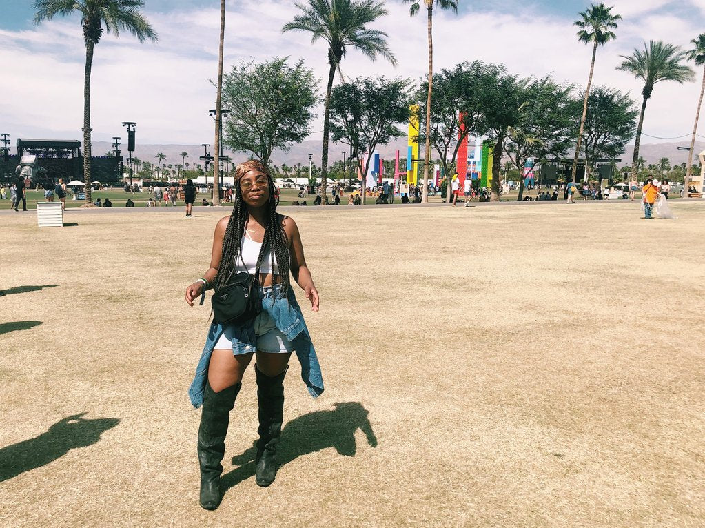 person with high boots posing, palm trees in the background.
