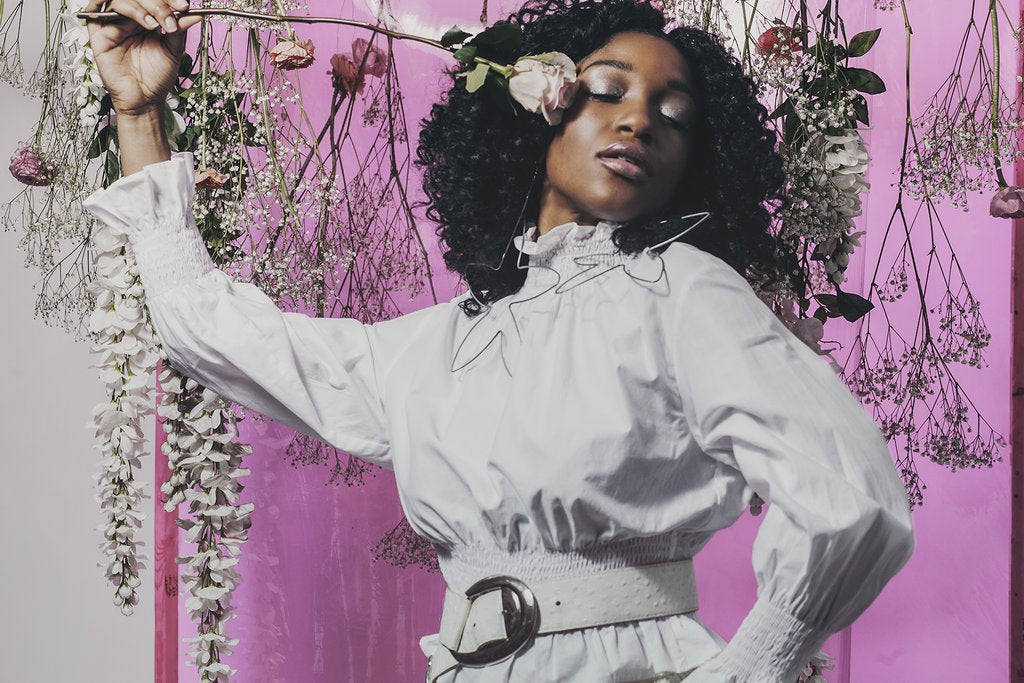 model holding rose in front of face.