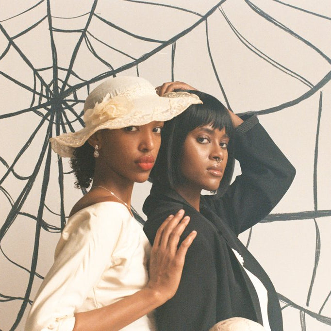 profile of two models in macabre bride and groom attire in front of a spider web set. 