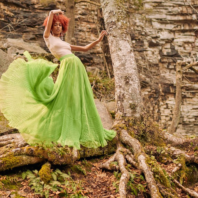 model in the woods posing with skirt floating. 