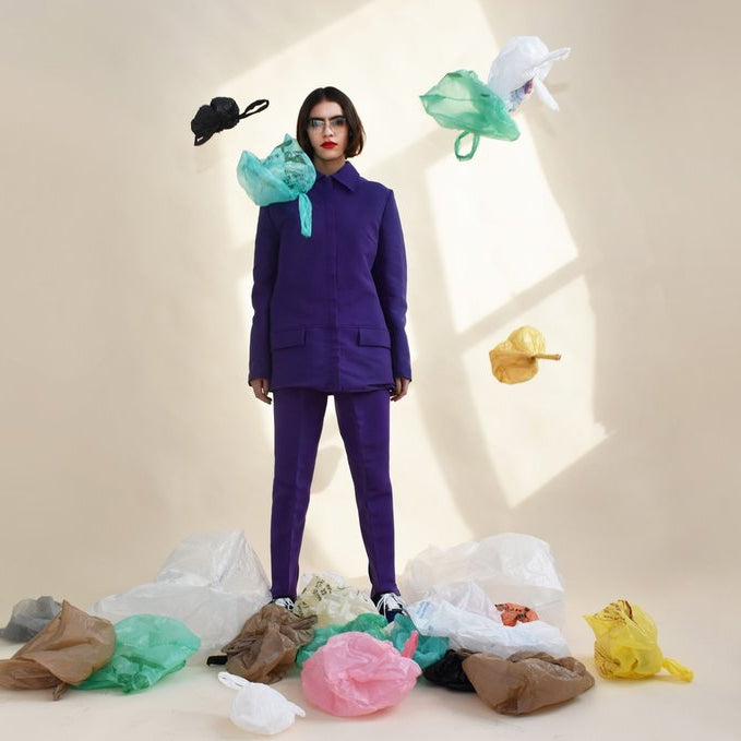 model in suit surrounded by plastic bags. 