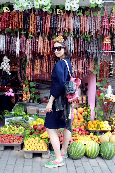 nina posing in front churchkhelas, old-fashioned georgian treats made from of grape juice and walnuts. at bottom, fruits like watermelon and strawberries.