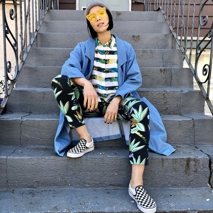 julee cerda in botanical print outfit and denim coat sitting on stoop.