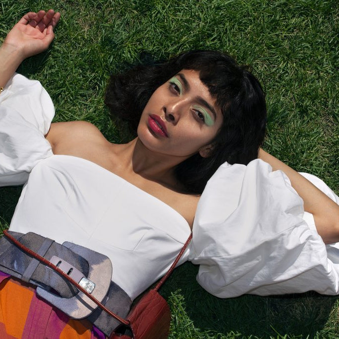model laying down posing in the grass with puffy sleeves. 