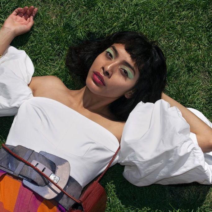 model laying down posing in the grass with puffy sleeves.