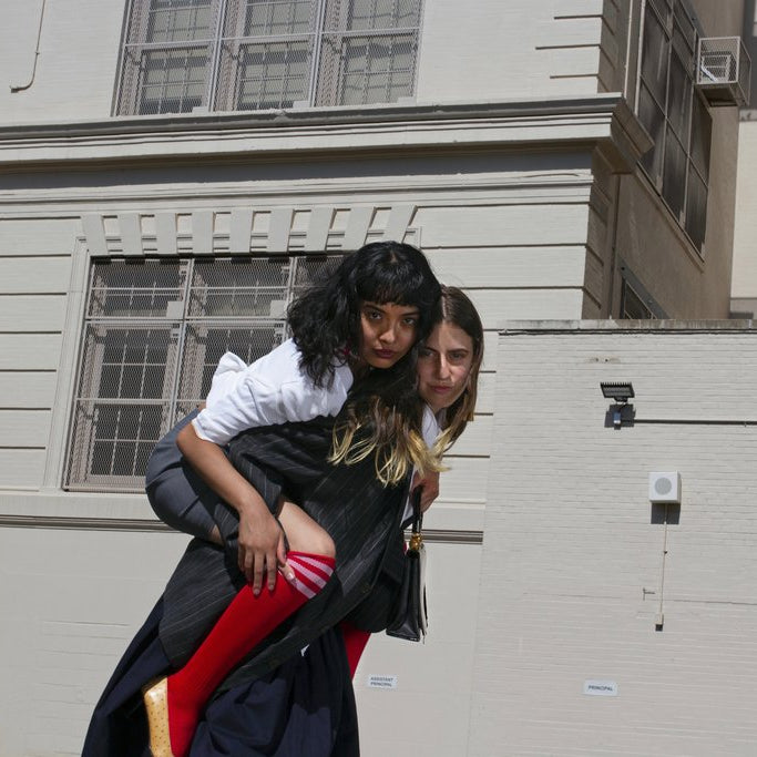 models in suiting giving one a piggy back ride in front of school building.