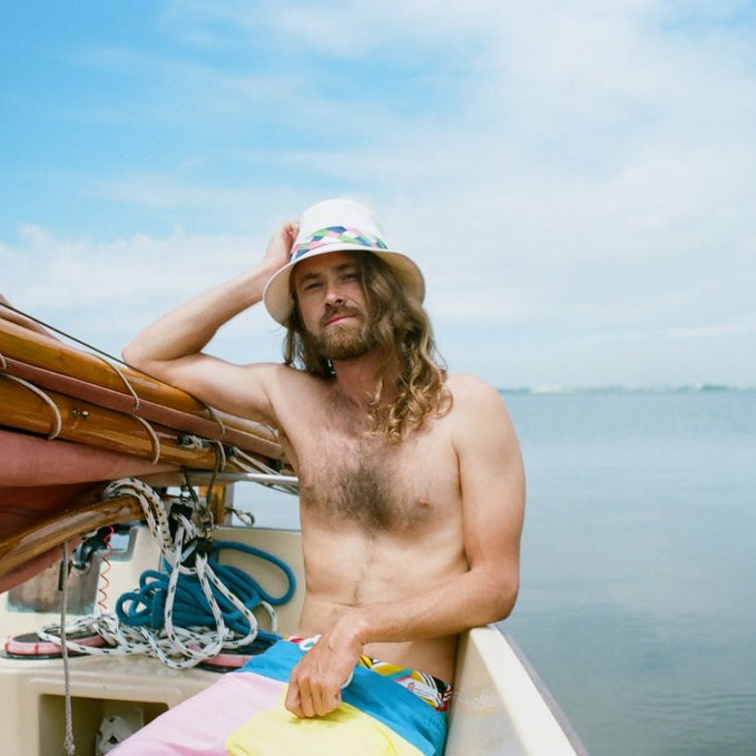 model seated and leaning on sail of sailboat. 