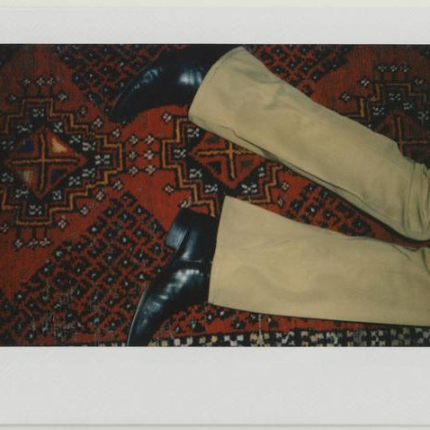detail of pants, boots on carpet.