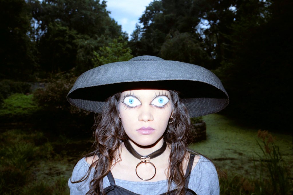 portrait of model with eyes painted on their face.
