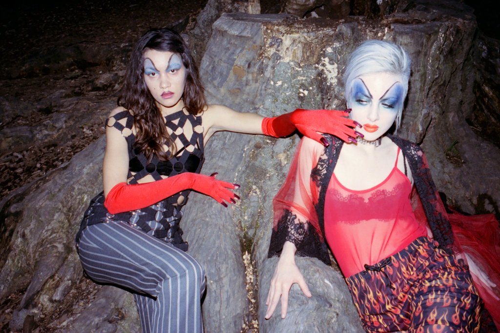 two models posing at a tree trunk.