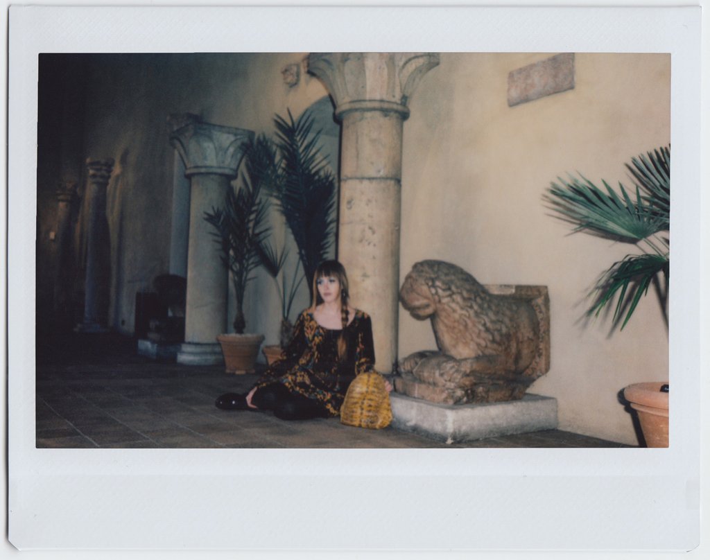 ana seated by pillar and statue.