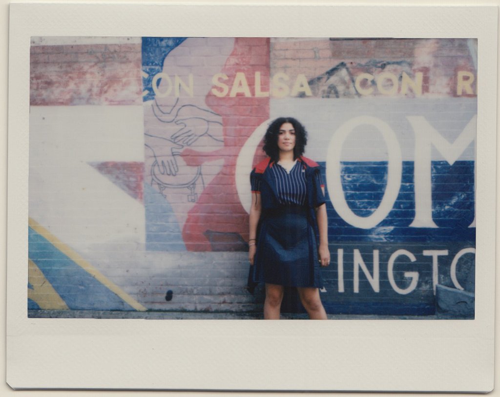 paola standing in front of painted wall.