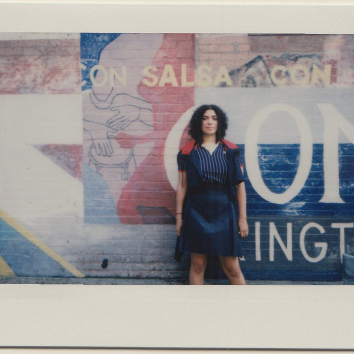 paola standing in front of painted wall.