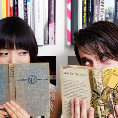 couple hiding behind books