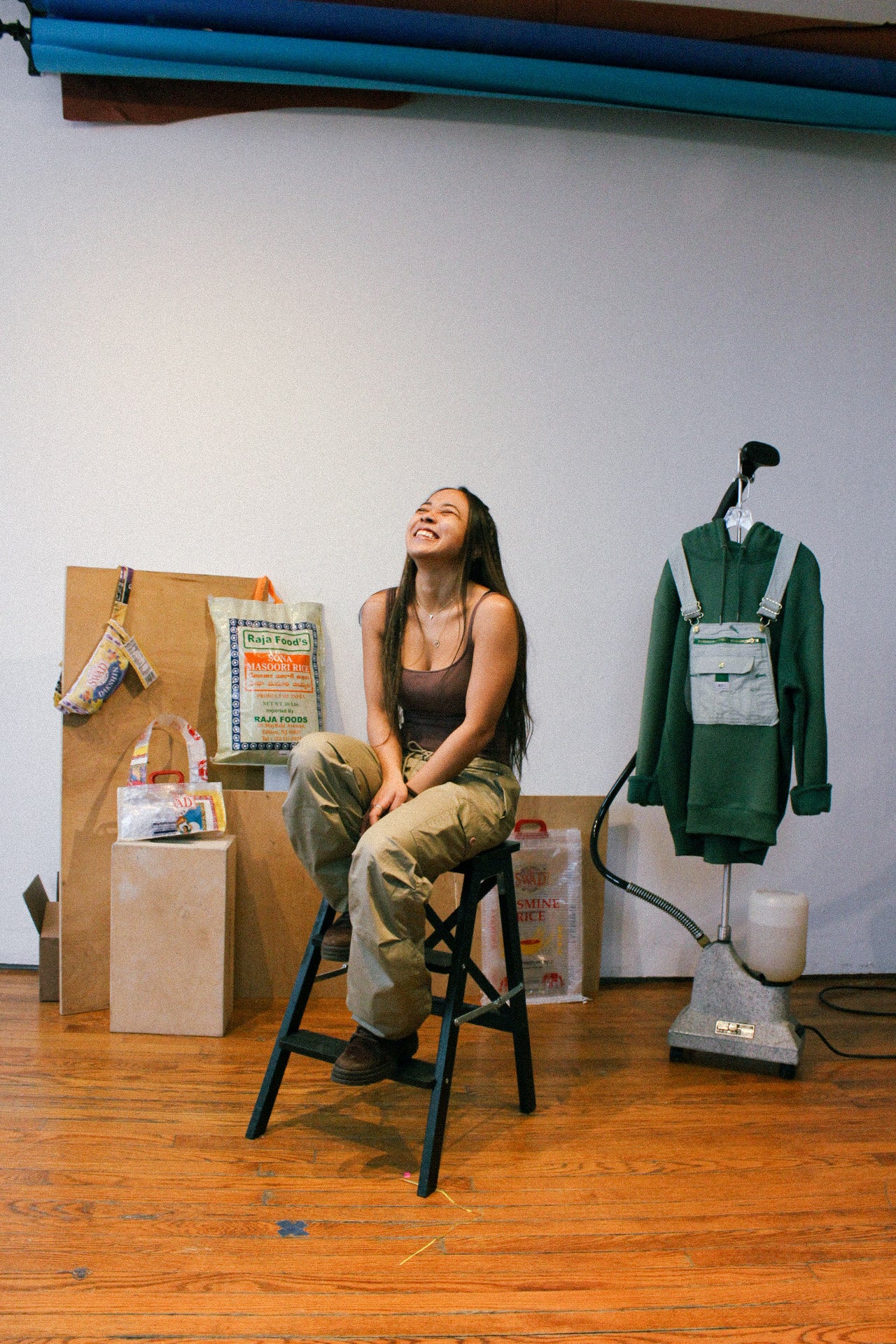 tania lekhraj seated on stool laughing in studio. 