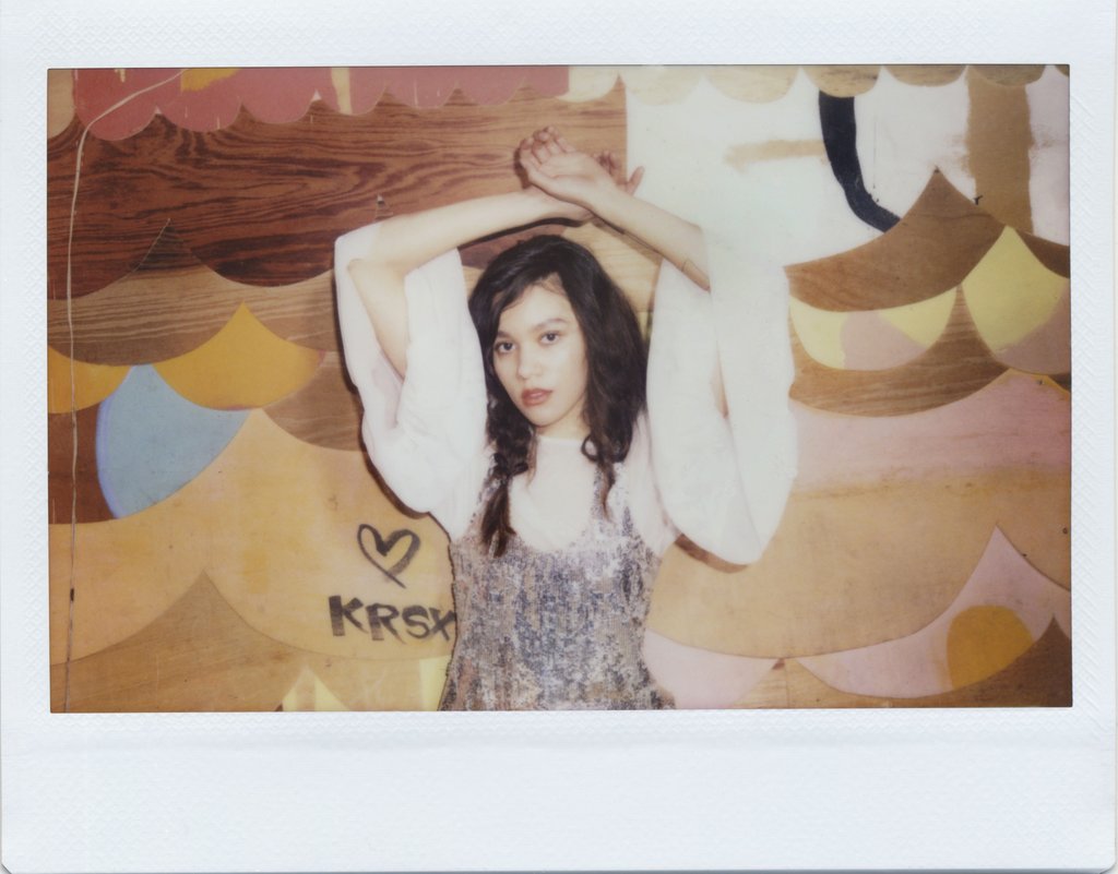 polaroid of model with arms above head.