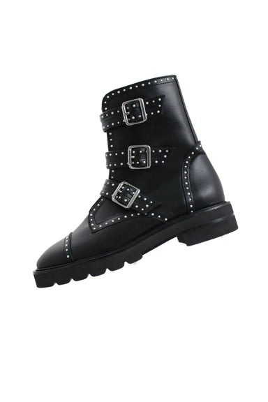 side angle of stuart weitzman black studded boots. features three adjustable silver buckles across front, rounded roe, rubber sole, and pearl studs throughout.