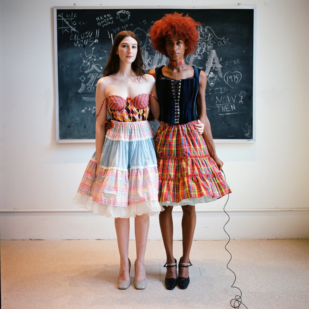 two models in front of chalk board with shutter release. 