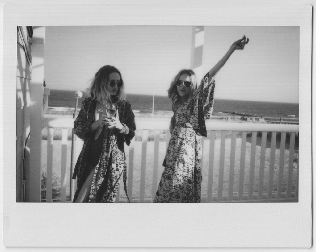 polaroid of two models on a balcony overlooking the beach. 