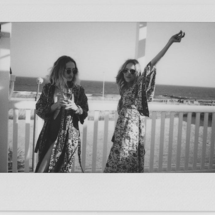 polaroid of two models on a balcony overlooking the beach. 