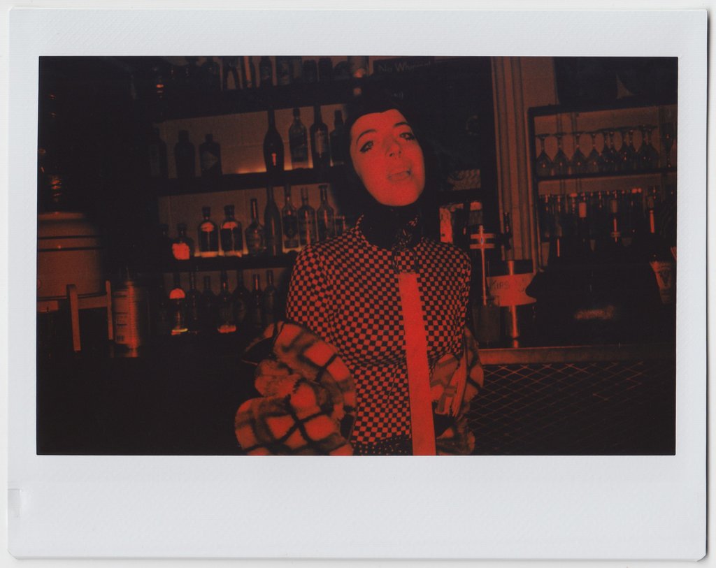person posing, bar in the background, all red effect in polaroid style. 