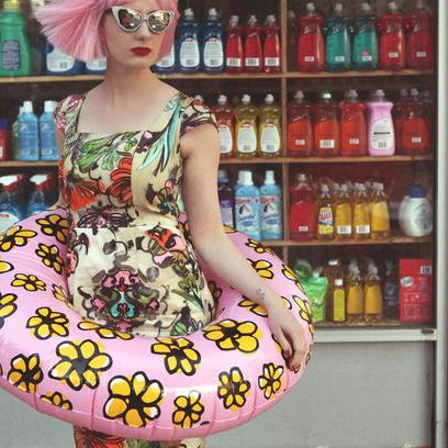 zuzu in gorgeous dress with ring pool float in front of a bodega. 