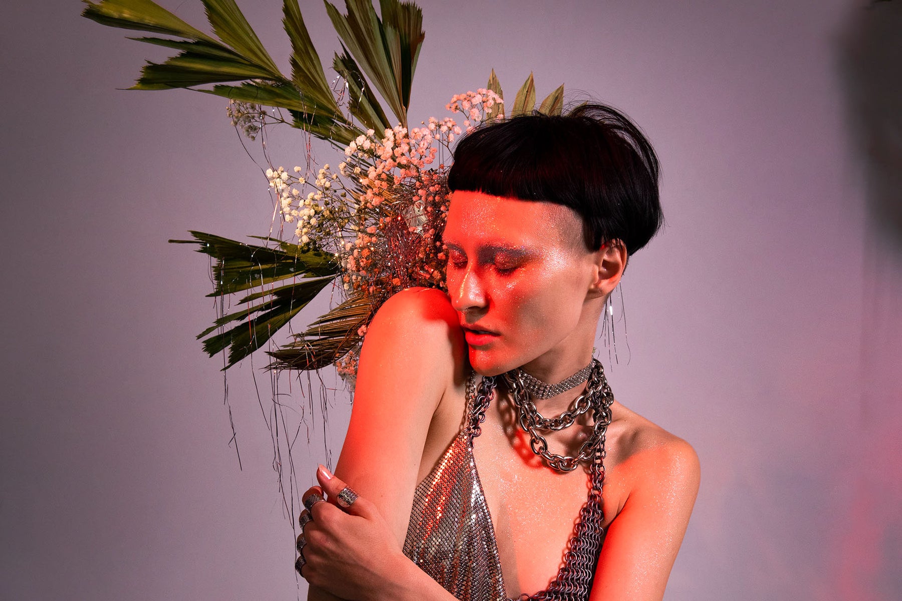portrait of a model in a silver look surrounded by a floral set. 