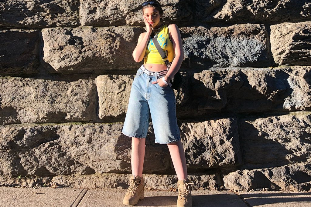 maheen in tank and 'tommy hilfiger' denim shorts in front of stone wall.