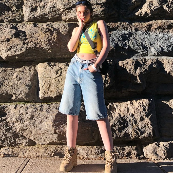 maheen in tank and 'tommy hilfiger' denim shorts in front of stone wall.