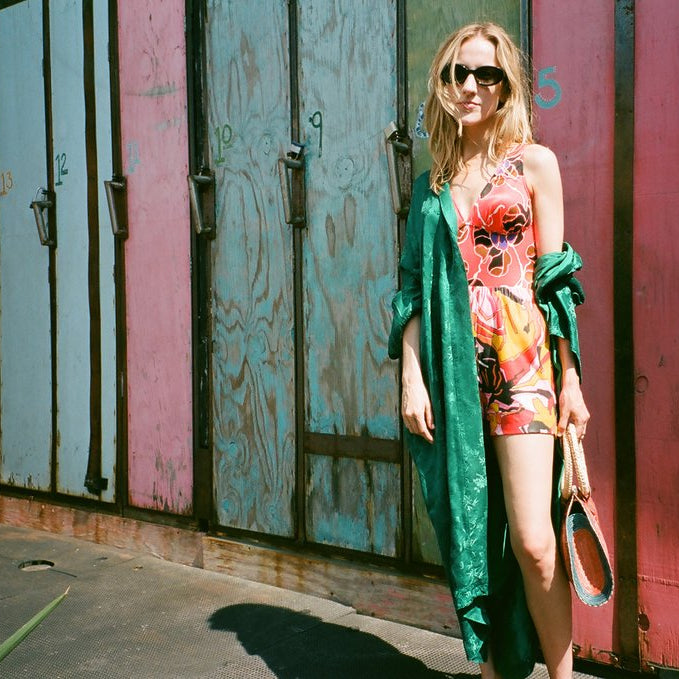 model in mixed prints and a silk robe in front of surf board lockers.