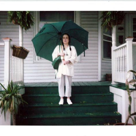 delcey standing on the steps, holding umbrella. 