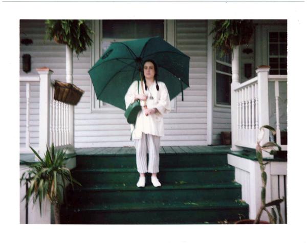 delcey standing on the steps, holding umbrella. 
