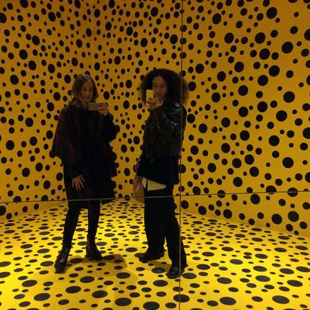 selfie in the mirror of sheyla and rachel in room with yellow and black dots.