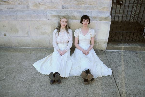 two models seated on stone wall. 