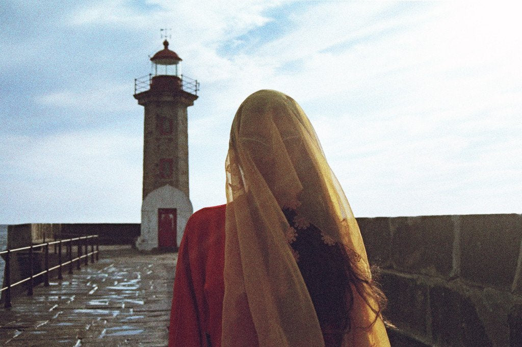aisha wearing a yellow veil in front of a lighthouse.