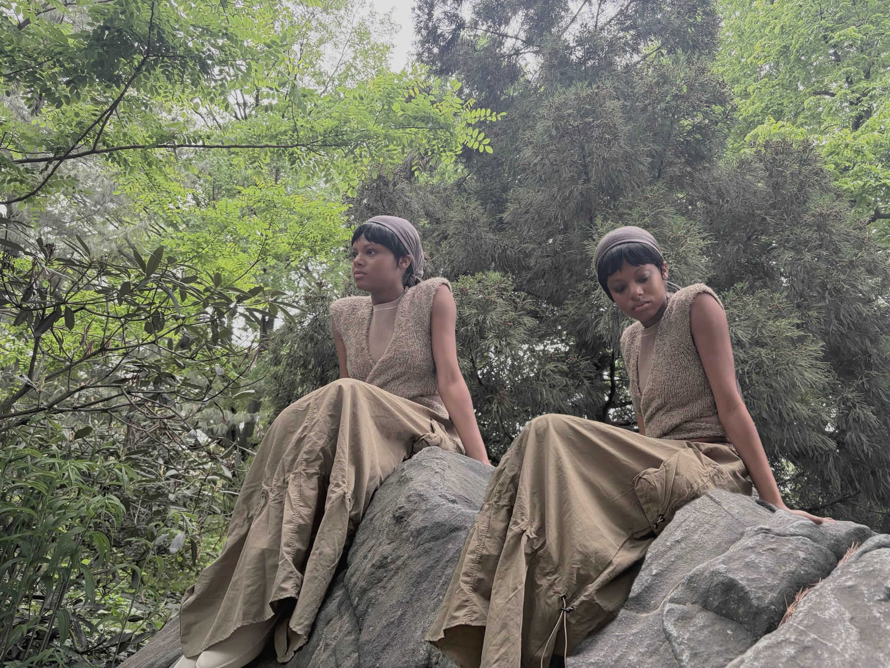 doubled image of model sitting on rock