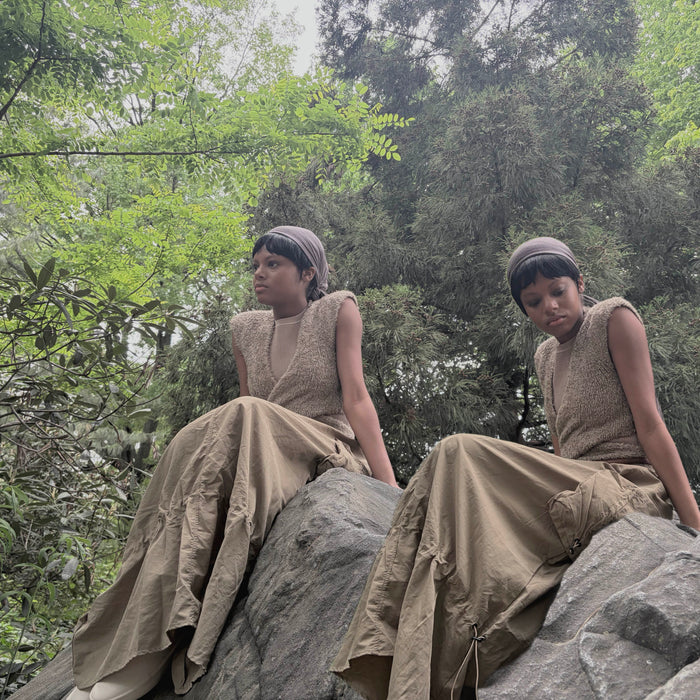 doubled image of model sitting on rock
