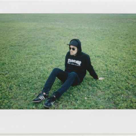 chris in thrasher hoodie sitting on grass. 