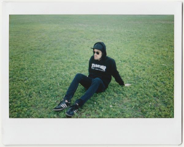 chris in thrasher hoodie sitting on grass. 