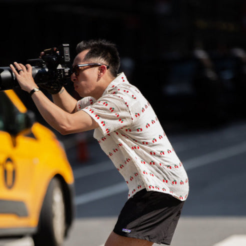 image oh pao holding a camera with taxi in background