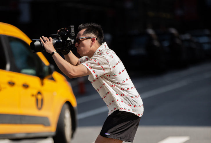 image oh pao holding a camera with taxi in background